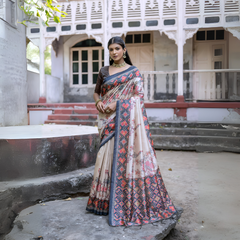 Woman wearing an off-white silk saree with blue and red Patola-inspired geometric and floral borders, featuring intricate floral motifs, paired with a matching blouse and traditional jewelry, elegantly posing on stone steps in front of a vintage heritage house with ornate wooden railings and classic architecture.Woman wearing an off-white silk saree with blue and red Patola-inspired geometric and floral borders, featuring intricate floral motifs, paired with a matching blouse and traditional jewelry, elegan