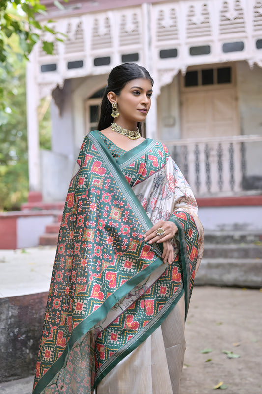 Woman wearing an off-white silk saree with green Patola-inspired geometric and floral borders, featuring intricate floral motifs, paired with traditional jewelry, elegantly posing on stone steps in front of a vintage heritage house with ornate wooden railings and lush greenery in the background.