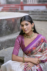 Woman wearing an off-white silk saree with purple Patola-inspired geometric and floral borders, featuring intricate floral motifs, paired with traditional jewelry, elegantly posing on stone steps in front of a vintage heritage house with ornate wooden railings and classic architectural details.

Related
File name: madhubani-embroidery-tussar-saree
Alt text: Traditional Madhubani embroidery on a Tussar silk saree highlighting intricate motifs.