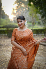 Smiling woman in orange saree with intricate zari work
