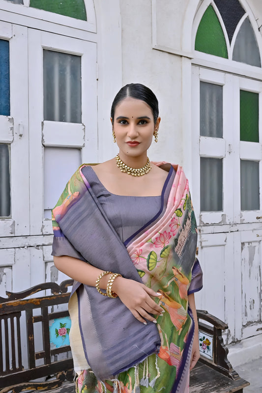 Woman wearing a pastel multicolor floral printed saree with a contrasting purple border and a grey blouse, accessorized with traditional gold jewelry, elegantly standing in front of classic white arched doors and windows beside a vintage wooden bench, with greenery and a floral arrangement in a heritage courtyard setting.
