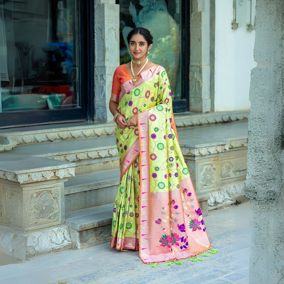 Woman wearing pastel pistachio green saree with intricate zari work and peach blouse in traditional Indian attire standing outdoors