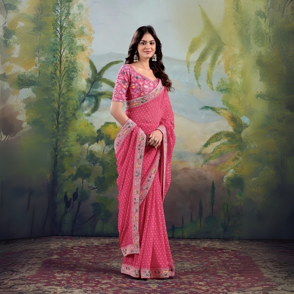 Woman wearing pink saree with floral embroidered border and matching blouse in studio backdrop