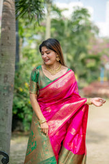 Woman dressed in a pink zari work saree with gold jewelry smiling and posing outdoors in a natural garden setting