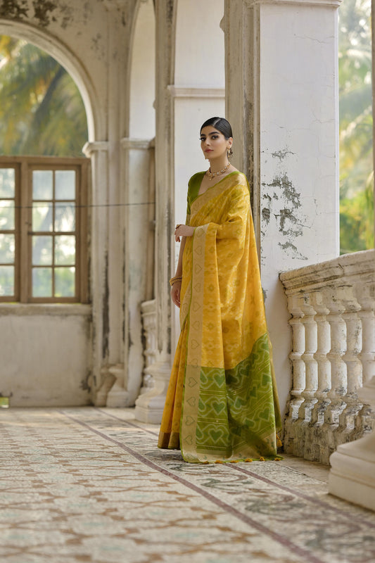 Woman wearing brown red Pochampali Ikkat saree with zari weaving, styled in a traditional elegant look on a heritage balcony
