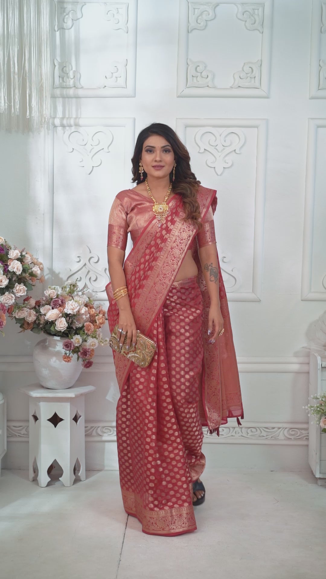 Woman wearing a red saree with a white pattern against a white background