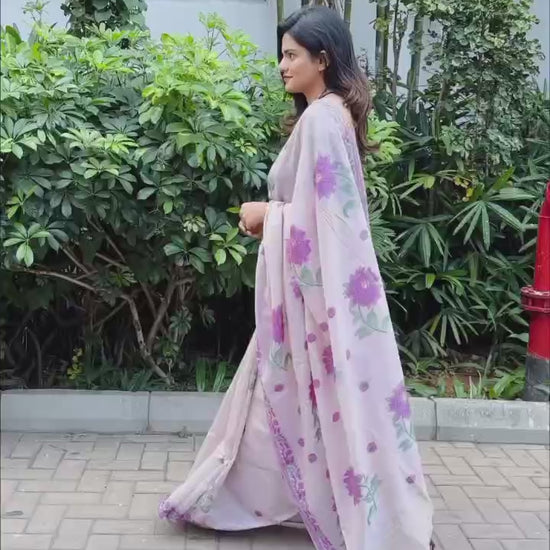 Woman in elegant purple resham weaving saree with floral motifs near plants
