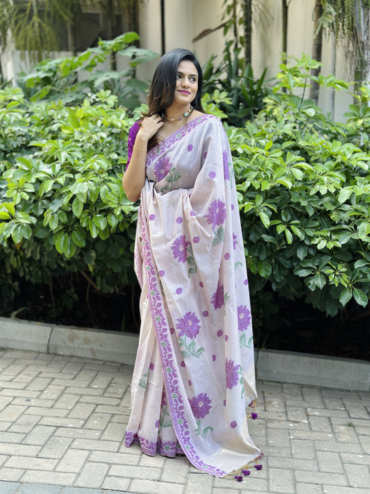 Woman in purple resham weaving saree with floral design standing in garden pathway