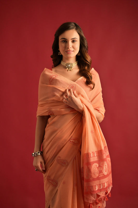 Woman wearing soft peach Resham weaving saree standing outdoors in traditional Indian ethnic attire
