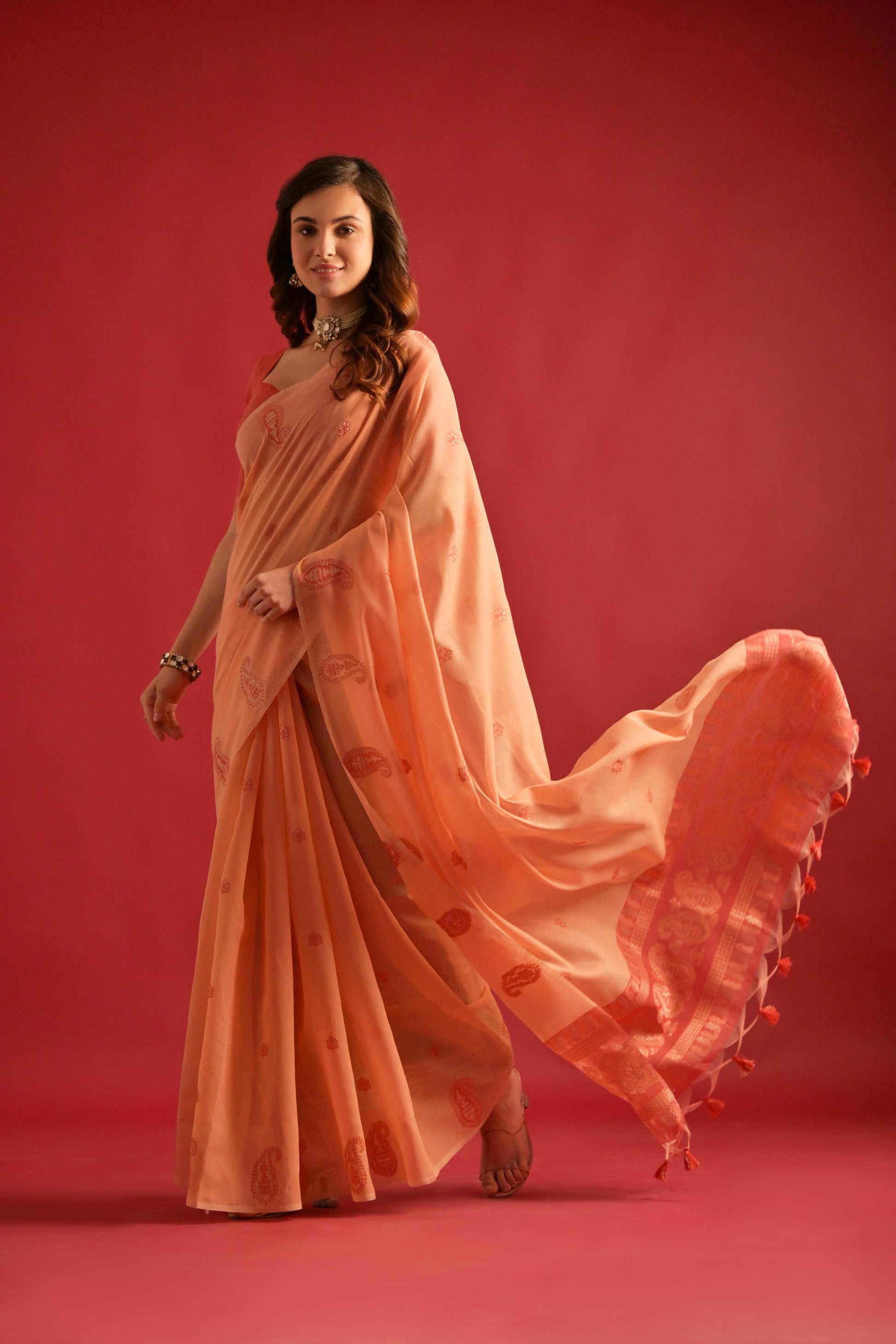 Woman wearing soft peach Resham weaving saree standing outdoors in traditional Indian ethnic attire