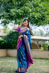 Elegant woman in teal blue zari work saree posing outdoors in traditional Indian attire with a graceful smile