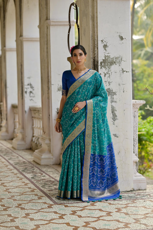Woman wearing teal Pochampali Ikkat saree with zari weaving, styled in a regal setting with timeless grace