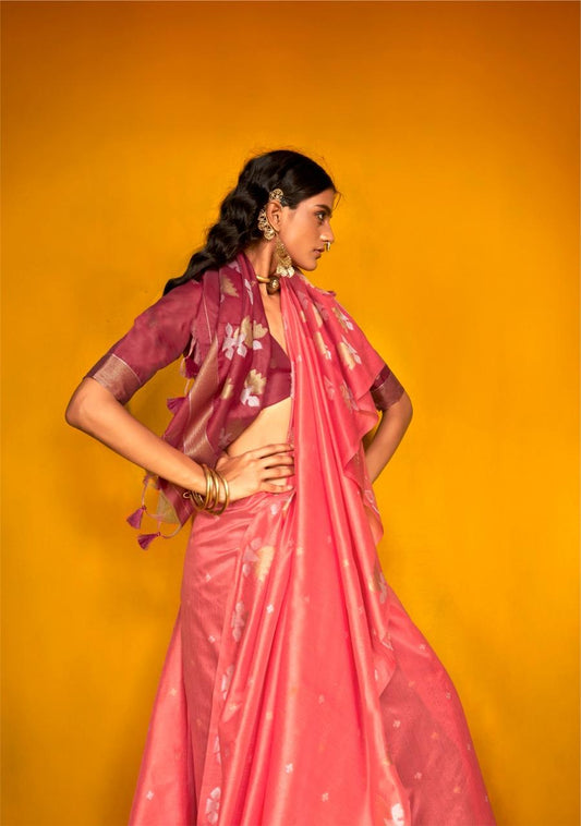 Model in tulip pink zari work silk saree posing in side view with ethnic jewellery against mustard yellow background