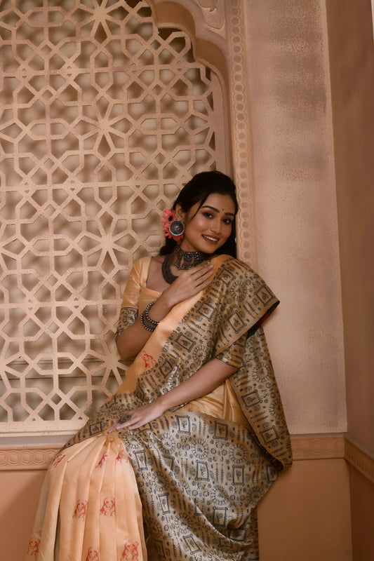 Woman wearing a cream silk saree with a grey geometric border and traditional jewelry, standing in a heritage-inspired room with ornate carved window and pastel walls