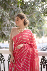 Woman wearing a pink saree with bold white geometric stripes and a floral embroidered pallu, standing on a balcony with decorative railing and lush green garden in the backgroundWoman wearing a pink saree with bold white geometric stripes and a floral embroidered pallu, standing on a balcony with decorative railing and lush green garden in the background