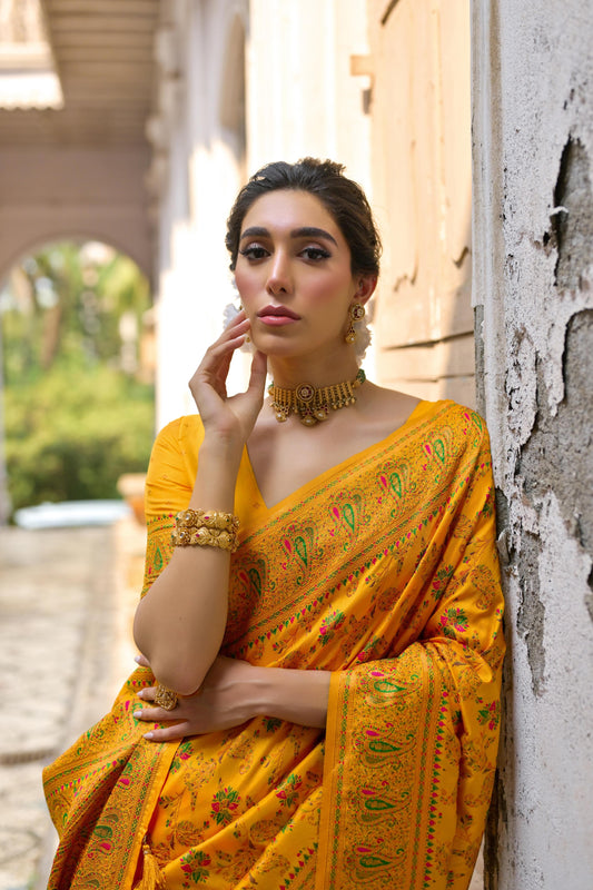 Woman wearing brown yellow Zari work saree standing outdoors in traditional Indian ethnic attire